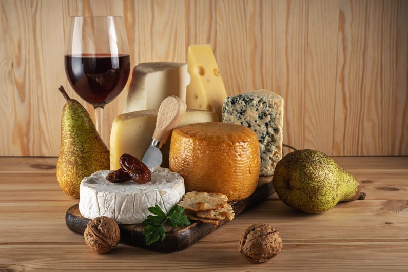 Various kind of cheese with glass of wine on wooden table. Cheese background.